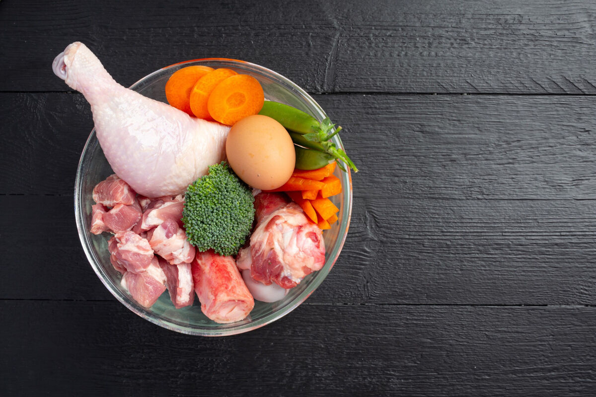 A bowl filled with meat, chicken, eggs, broccoli, carrots, and peas