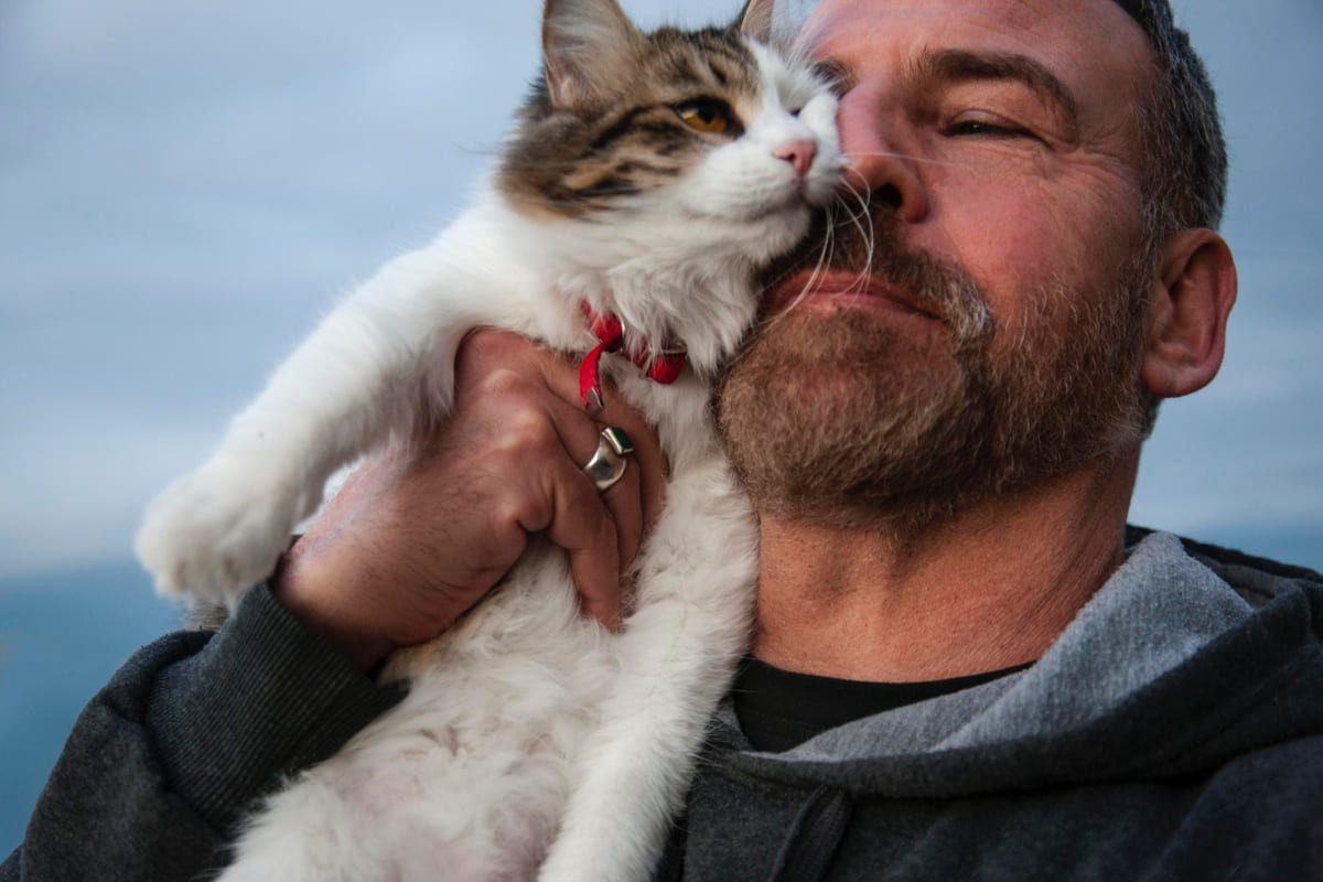 Man lifting his cat up and bringing it close to his face