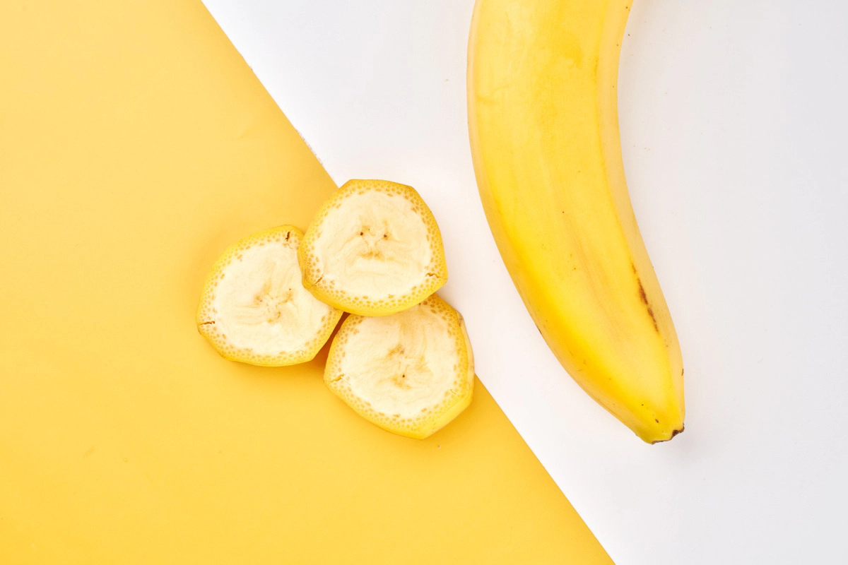 A whole banana and banana slices with peel next to it