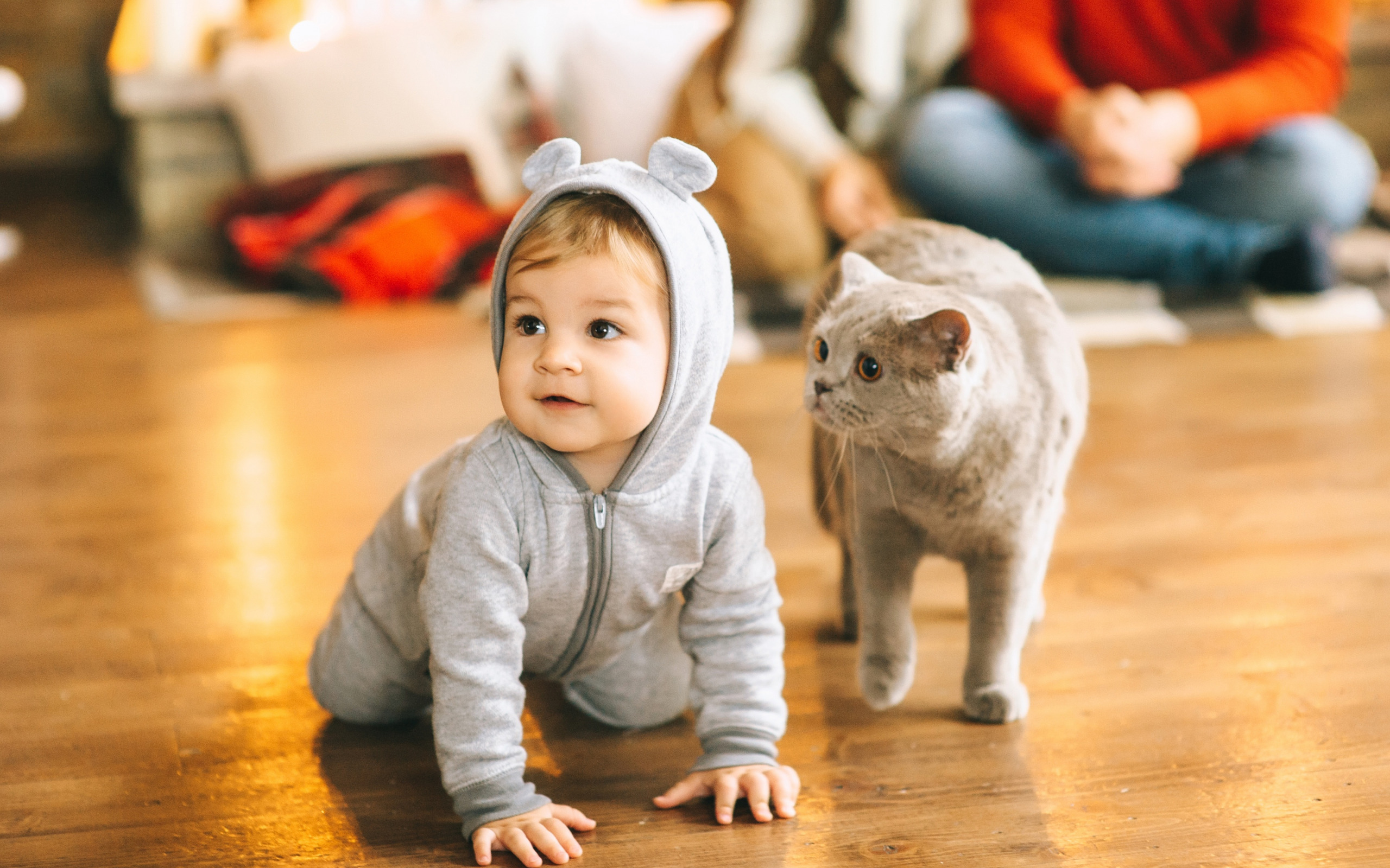 Cat standing next to a crawling baby