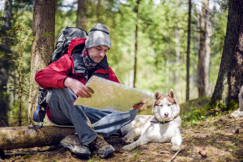 Camper sitting with their dog in nature