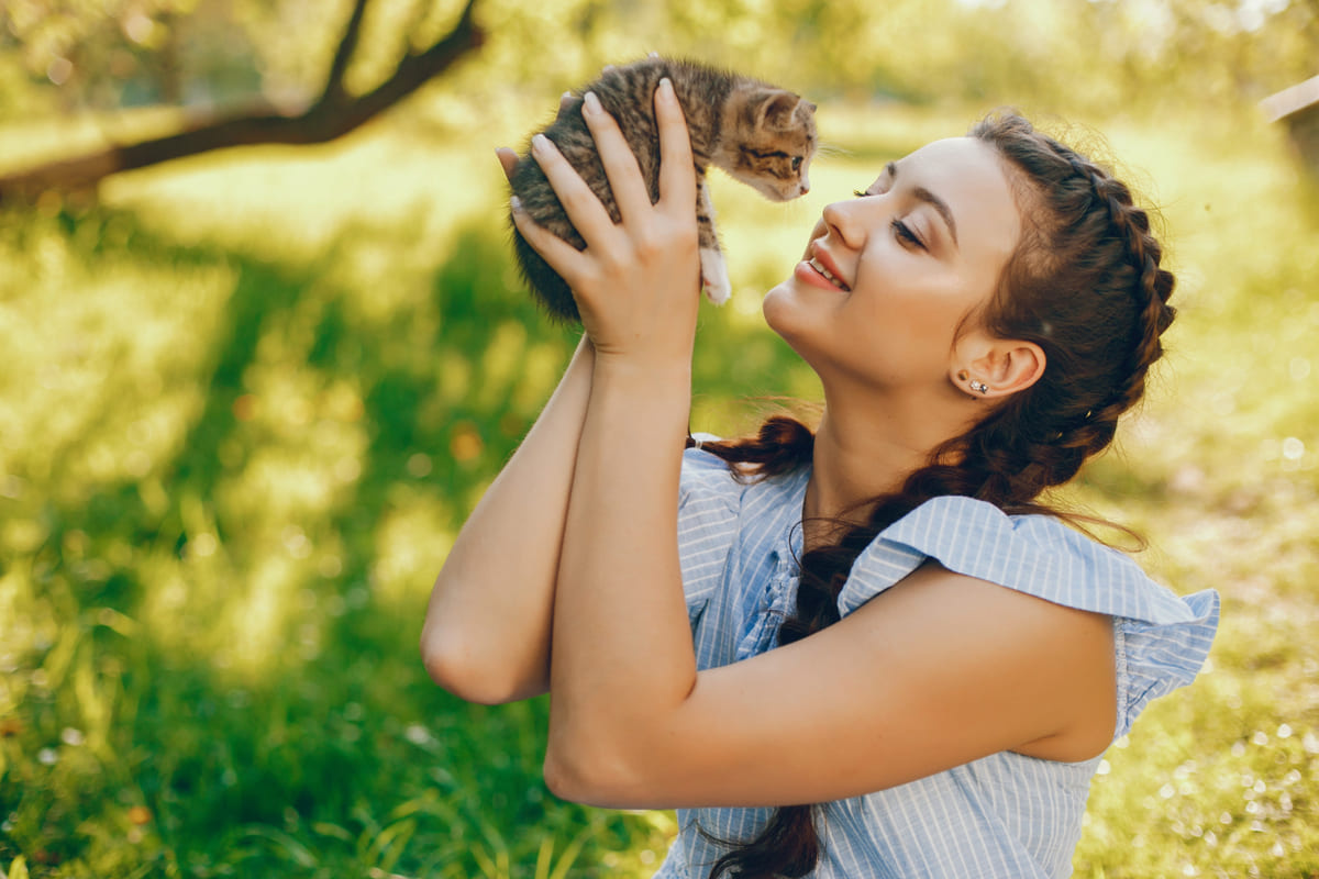 Girl picking up a kitten in an open area