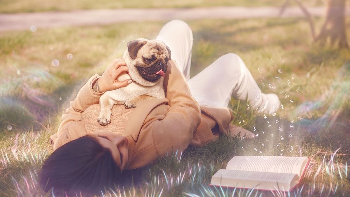 Woman lying on the grass with a pug lying on her
